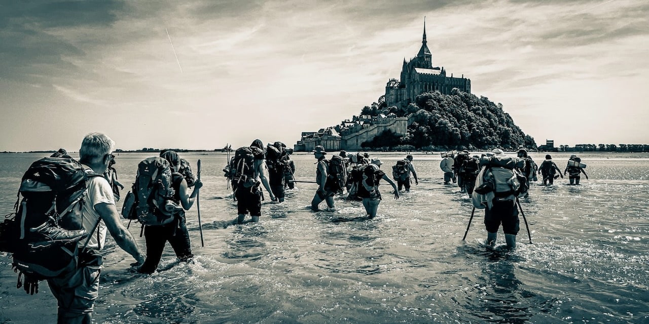 Photo des marcheurs dans la baie du Mont-Saint-Michel qui traversent le Couesnon